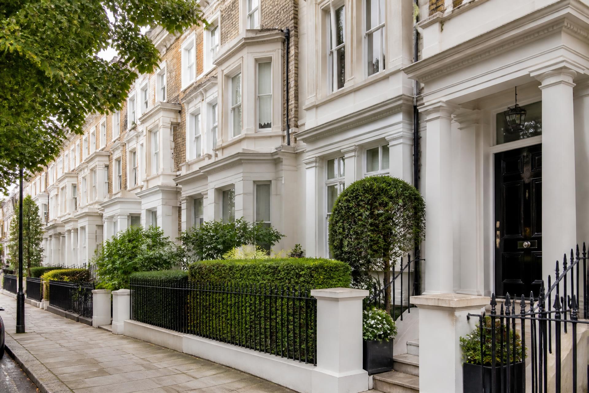 A row of white stucco and brick British terraced houses with black railings and glossy front doors